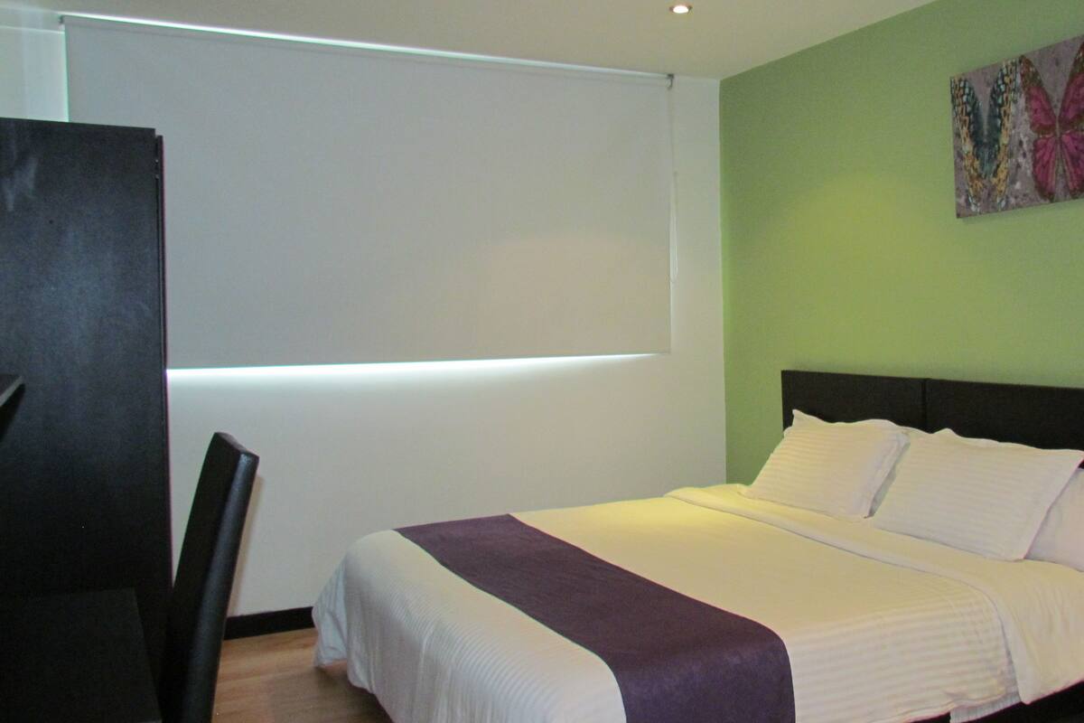 A hotel room with a bed, a desk, and a chair.