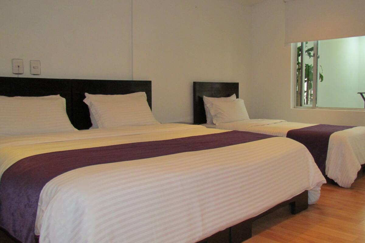 A hotel room with two beds, a window with a view, and a mirror on the wall.