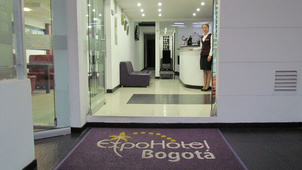 A hotel reception area with a receptionist, a reception desk, and a waiting area with a sofa.