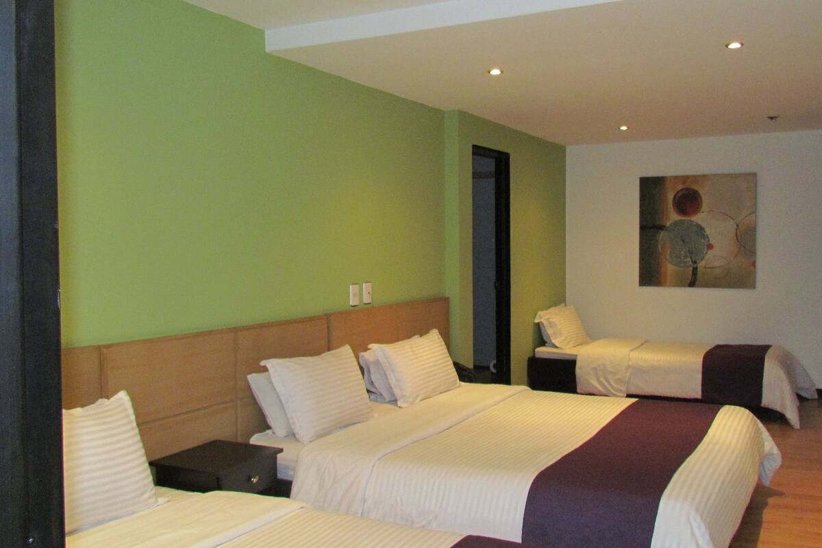 A hotel room with two beds, a nightstand, and a painting on the wall.