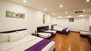 A hotel room with three beds, wooden flooring, and artwork on the walls.