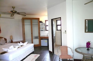 A hotel room with a bed, a desk, a chair, a small table with a vase, and a mirror. - Mango Spa Country Club (Hua Hin)