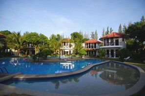 A swimming pool with lounge chairs and a building with a red roof. - Mango Spa Country Club (Hua Hin)