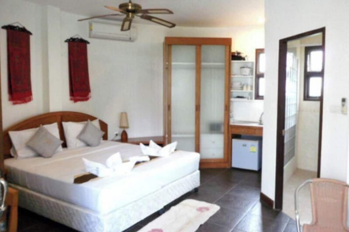Une chambre à coucher avec un lit, un ventilateur de plafond, un bureau et un miroir.