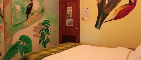 Una habitación con cama, puerta y paredes decoradas con pinturas de aves.