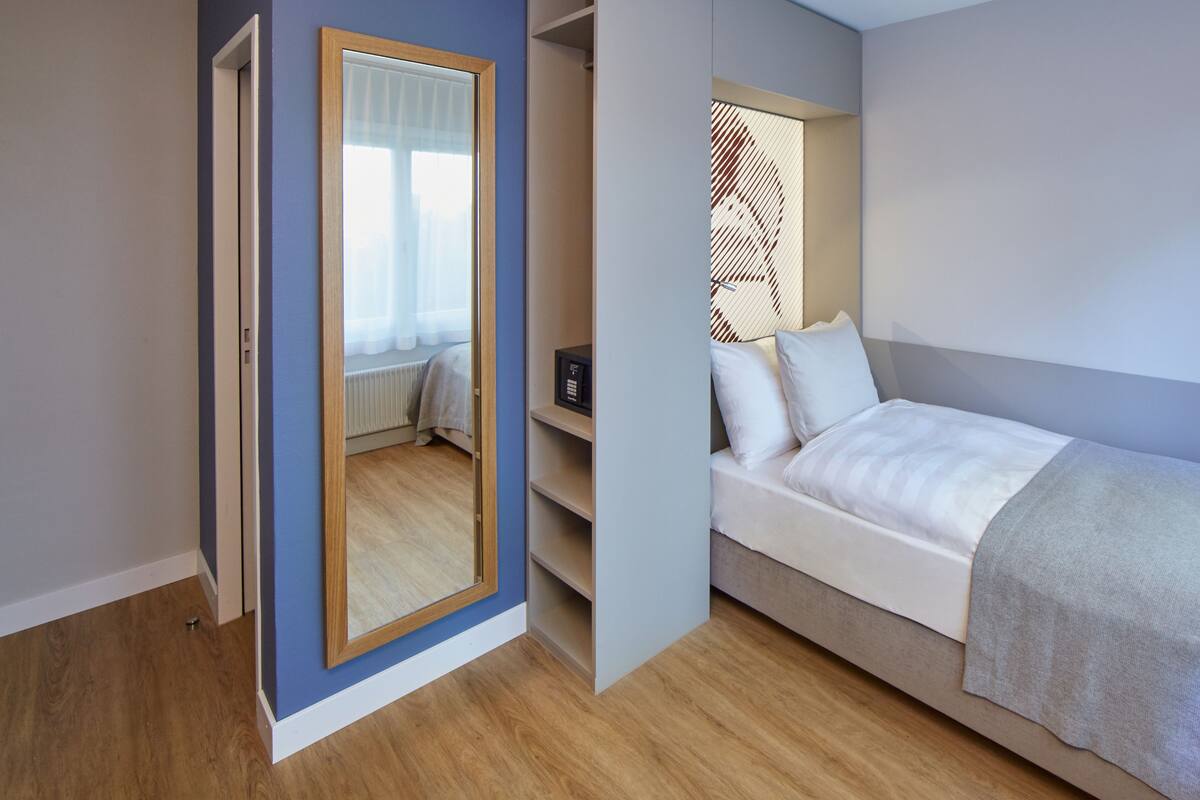 A bedroom with a bed, a wardrobe, and a mirror.