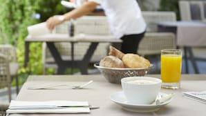Una mesa de desayuno con un bol de pasteles, un vaso de zumo de naranja y una taza de café.