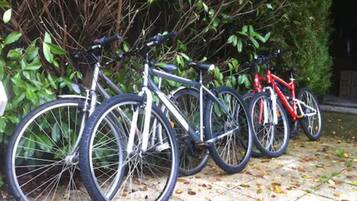 Varias bicicletas aparcadas sobre una superficie pavimentada, con un seto de fondo.