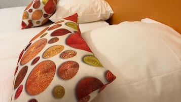 A hotel room with a bed, white bedding, and a headboard with a light fixture.