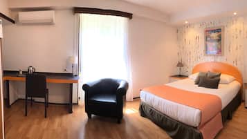 Una habitación de hotel con cama, escritorio, silla y aire acondicionado.