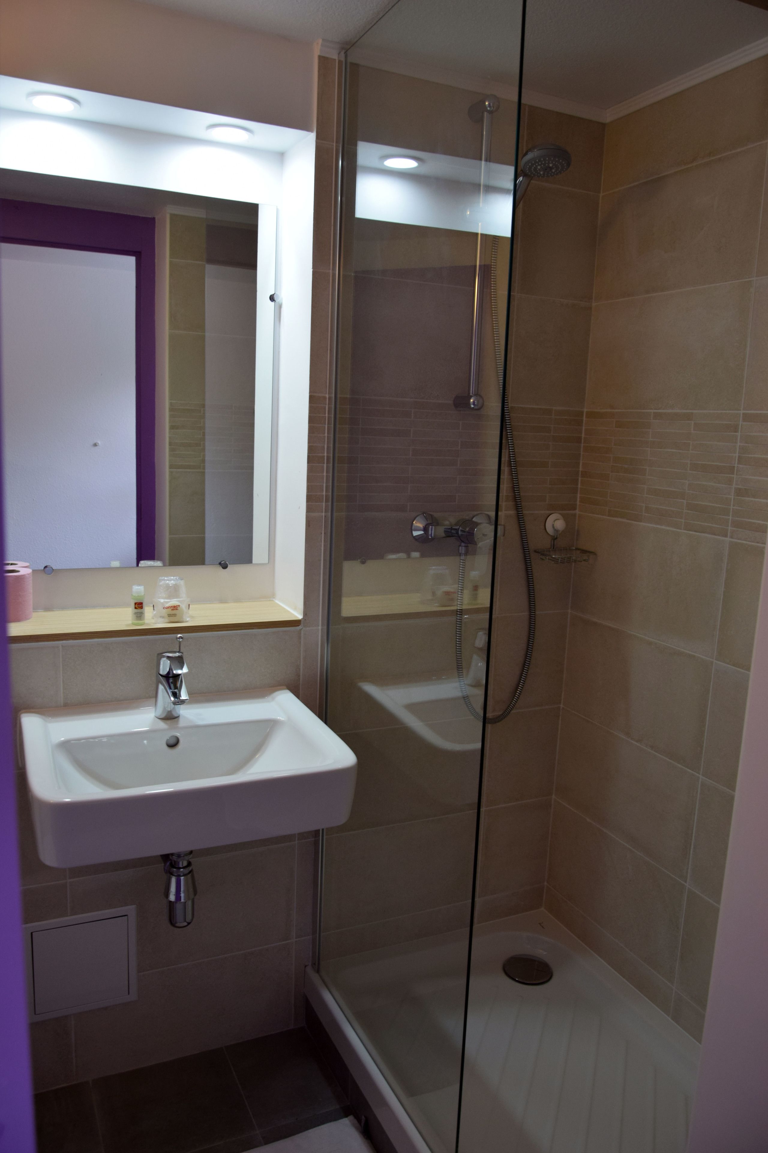 Une salle de bain avec une douche à parois de verre, un lavabo et un miroir.