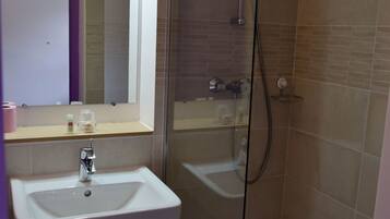 Une salle de bain avec une douche à parois de verre, un lavabo et un miroir.
