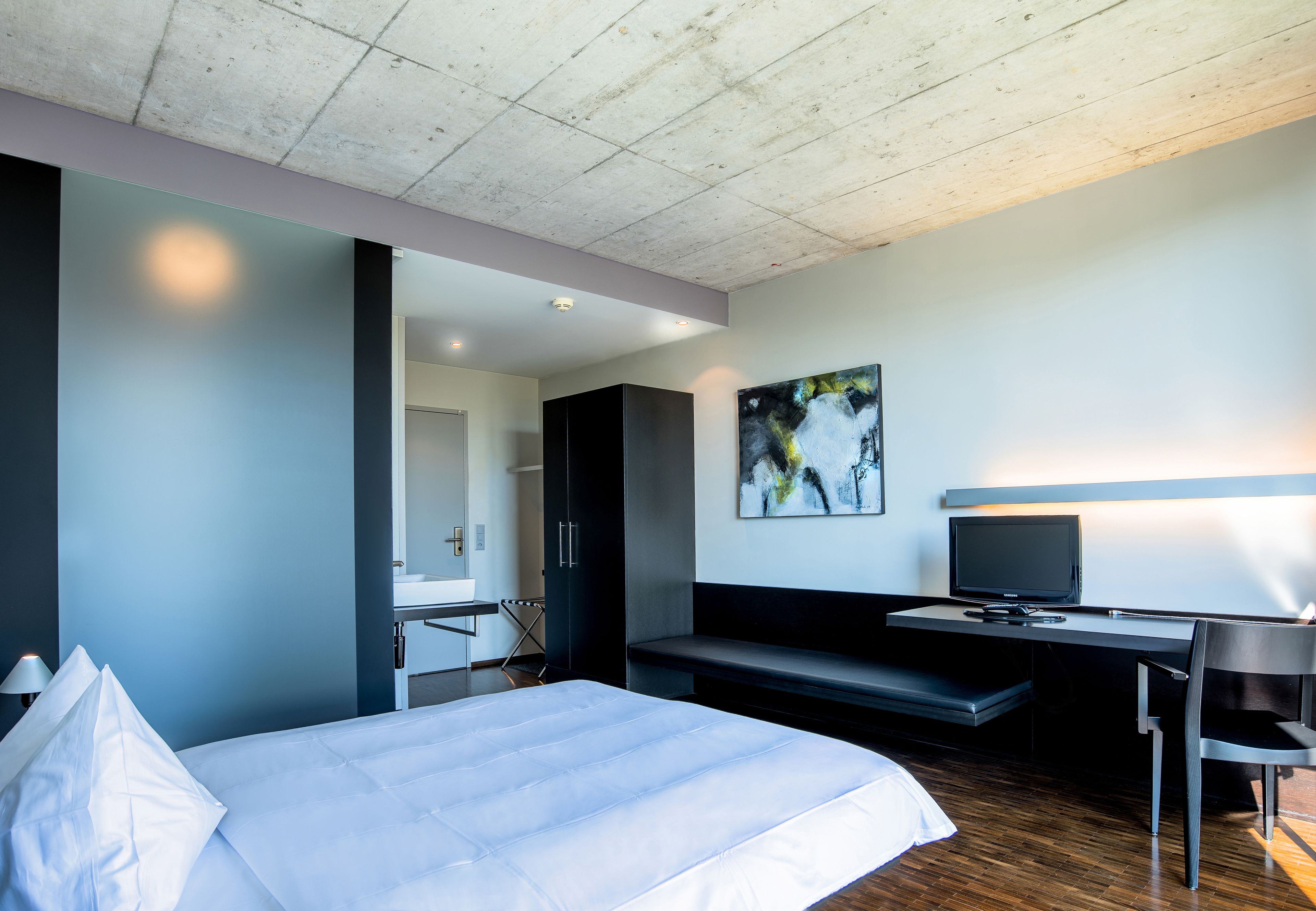 Une chambre d’hôtel moderne équipée d’un grand lit, d’un bureau avec un ordinateur et d’une télévision.