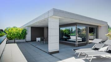 Eine moderne Außenpatio mit Betonböden, Glaswänden und Lounge-Stühlen.
