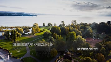 Vue aérienne du parc Seeburgpark à Kreuzlingen, avec un lac, de vastes pelouses verdoyantes et des arbres.