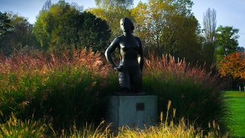A statue in a park with tall grasses and trees in the background.