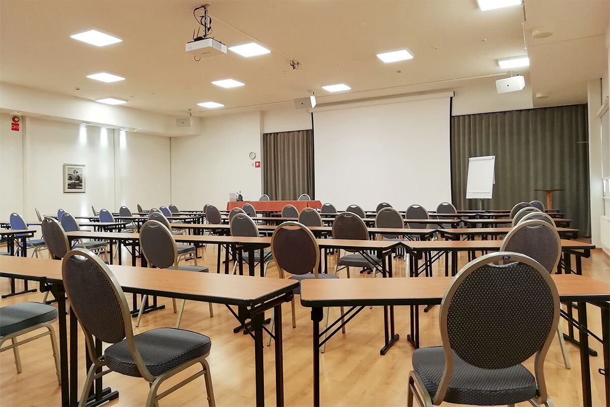 A conference room with multiple tables and chairs, a projector, and a whiteboard.