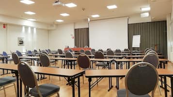 A conference room with multiple tables and chairs, a projector, and a whiteboard.