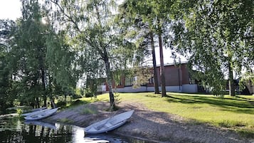 Joenrantavyöhyke, jossa on laivoja laiturissa, puita ja taustalla näkyvä rakennus.