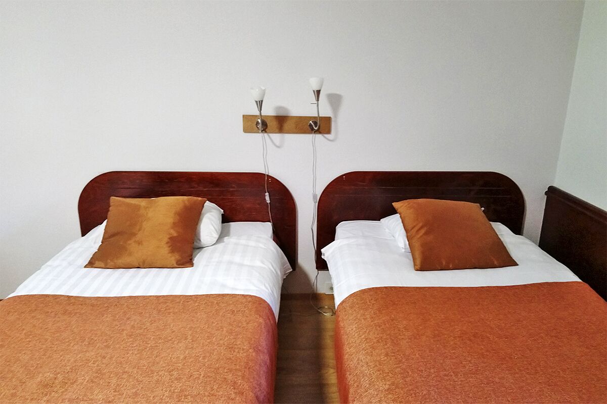 Una habitación con dos camas, cada una con cabecero y almohada marrones.