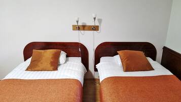 Una habitación con dos camas, cada una con cabecero y almohada marrones.