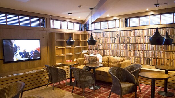 Una biblioteca con estanterías, un televisor y zonas de estar.
