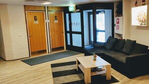 A reception area with a wooden reception desk, a black sofa, and two wooden doors marked as WC. - Hotelli Vuolake (Laukaa)