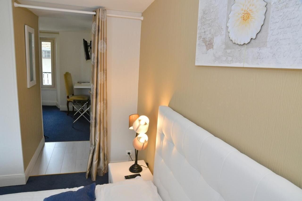 Una habitación de hotel con una cama, una mesita de noche con una lámpara, una silla y un cuadro en la pared.