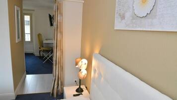 Una habitación de hotel con una cama, una mesita de noche con una lámpara, una silla y un cuadro en la pared.