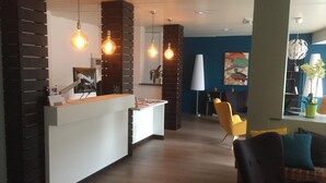 Una moderna area reception con un bancone bianco, dettagli in mattoni e lampade a sospensione.