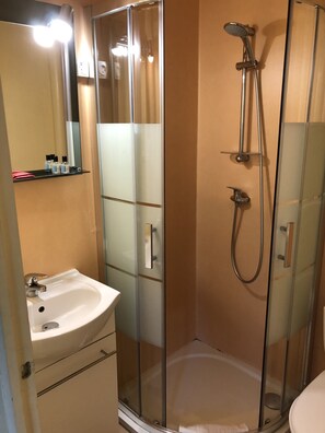 A modern bathroom with a glass-enclosed shower, a white sink, and a mirror above the sink. - Hôtel Restaurant Saint-Benoît (Gueugnon)