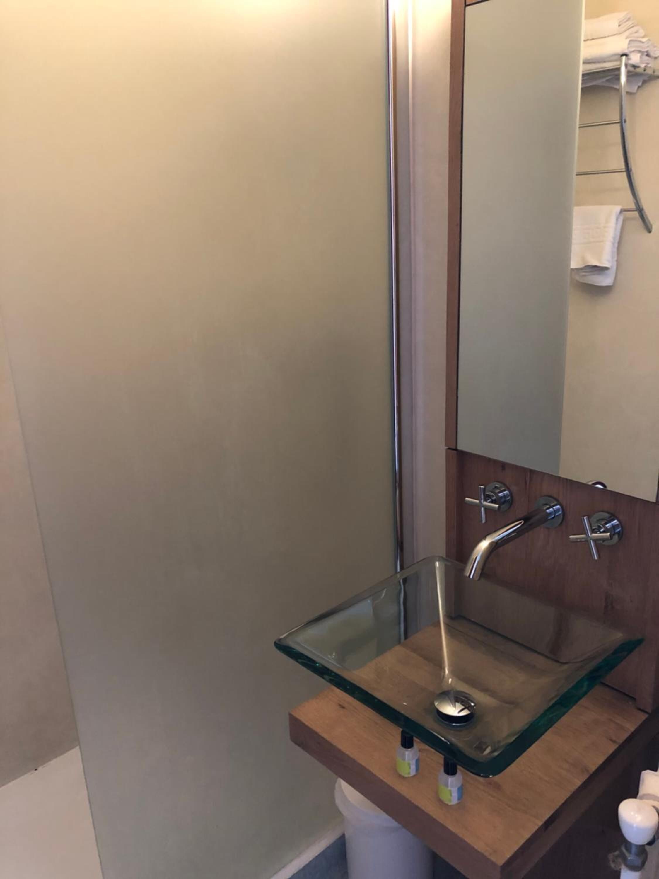 A bathroom with a glass sink, wooden countertop, and a mirror.