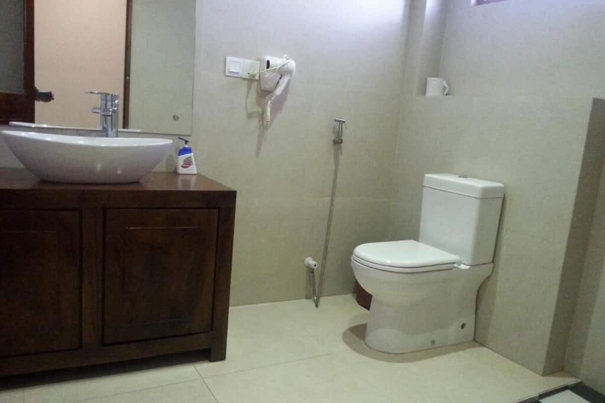 A bathroom with a wooden vanity, a white sink, a toilet, and a shower.