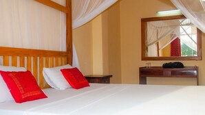 A hotel room with a bed, a nightstand, a mirror, and a window with curtains.