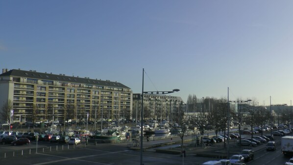 Un hôtel à plusieurs étages, doté d’une architecture moderne, avec des balcons et un parking où sont stationnées des voitures.