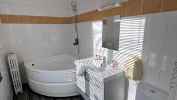 Et badeværelse med badekar, toilet og håndvask.