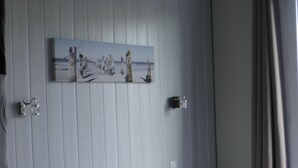 A hotel room with a bed, a nightstand, a wall-mounted artwork, and a window with curtains. - Hôtel de L'Univers (Caen)
