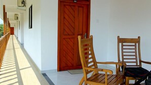Un pasillo con una puerta de madera, dos sillas de madera y una mesita.