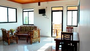 Una habitación amplia con sofá, mesa de comedor y sillas. Cuenta con ventanas grandes que dejan entrar luz natural y ofrecen vistas al exterior.