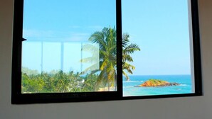 Una ventana con vista a una playa tropical, palmeras y un cielo despejado.