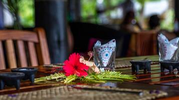 Una mesa de comedor con un centro de mesa de flor roja, servilletas estampadas y pequeños candelabros negros.