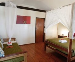 Una habitación con cama, piso de madera, puerta y un cuadro colgado en la pared.