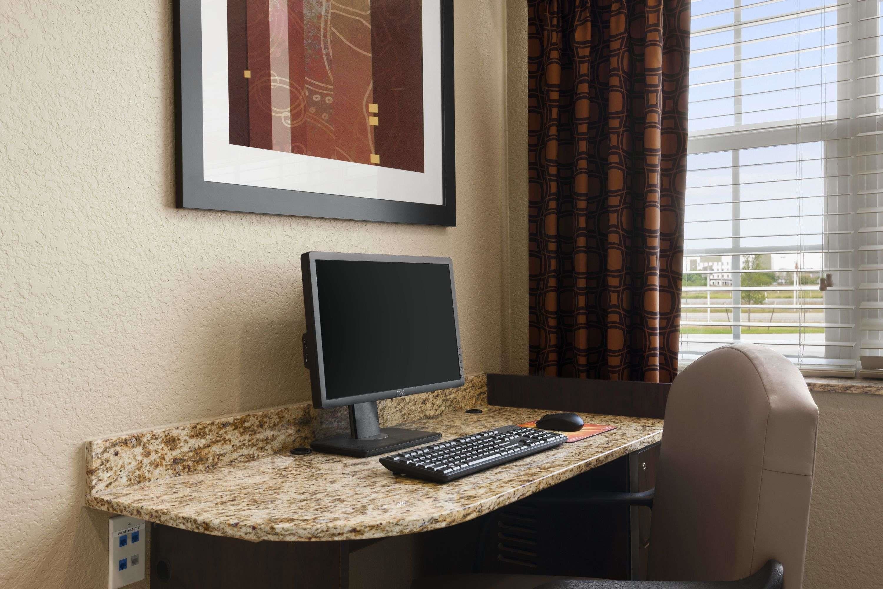 A computer desk with a monitor, keyboard, and mouse.