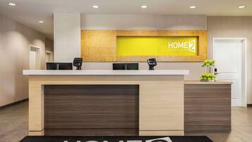 A reception desk with a 'HOME 2' sign, a black telephone, and a small plant on the counter.