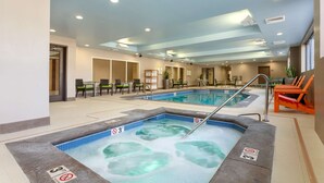 Una piscina interior con hidromasaje, zonas de estar e iluminación empotrada en el techo.
