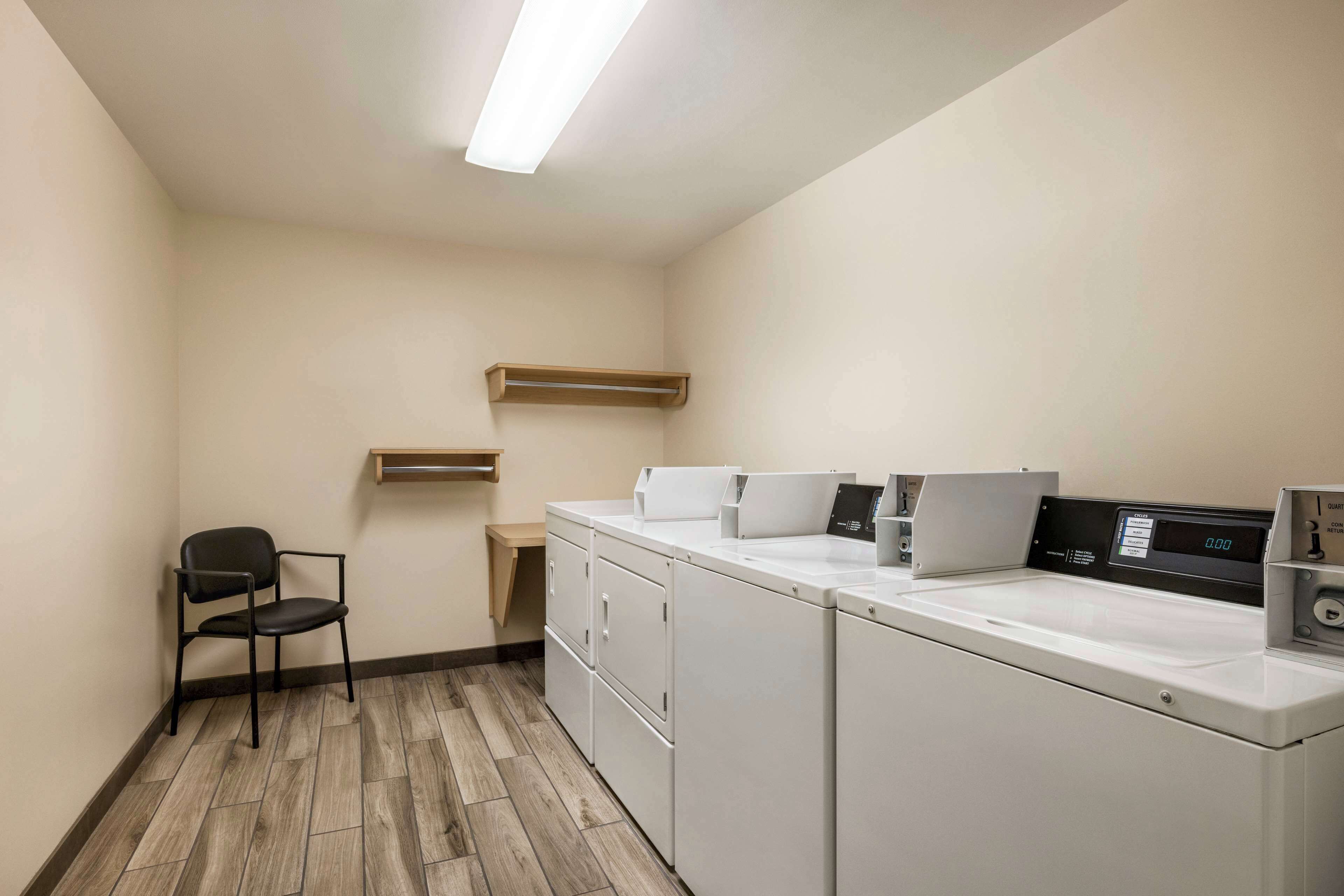 A laundry room with a chair, a washing machine, and a dryer.