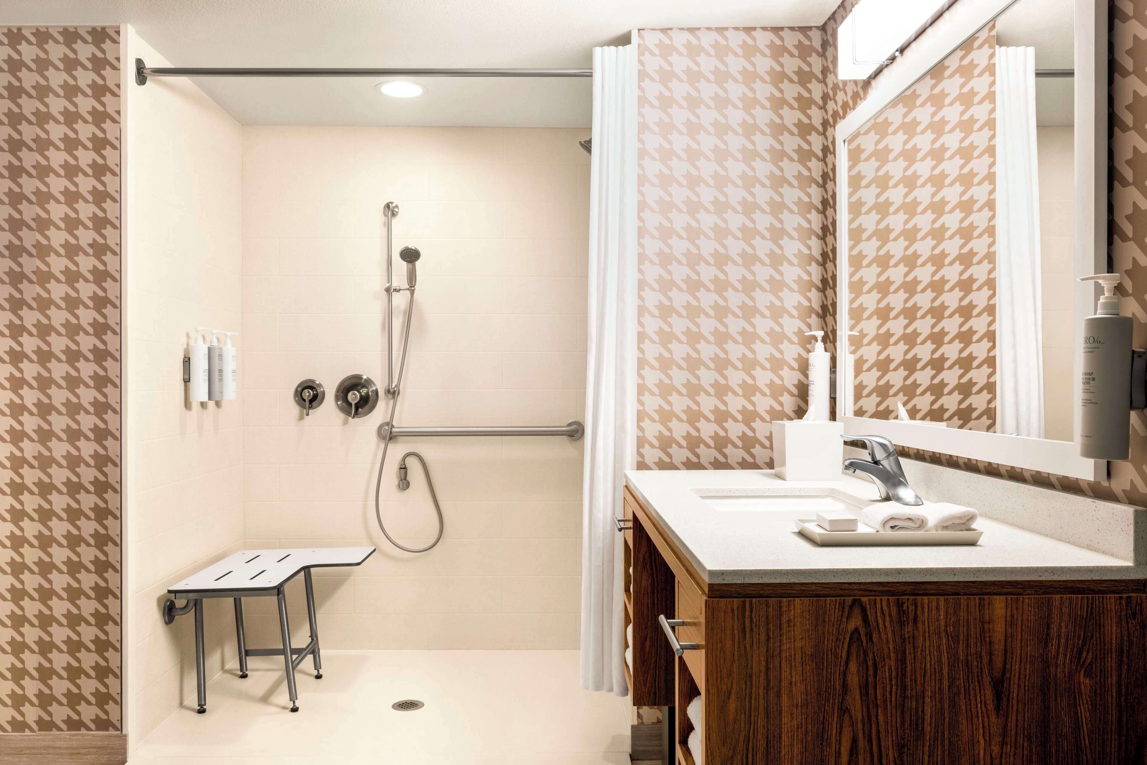 Een moderne badkamer met douche, wastafel en spiegel.