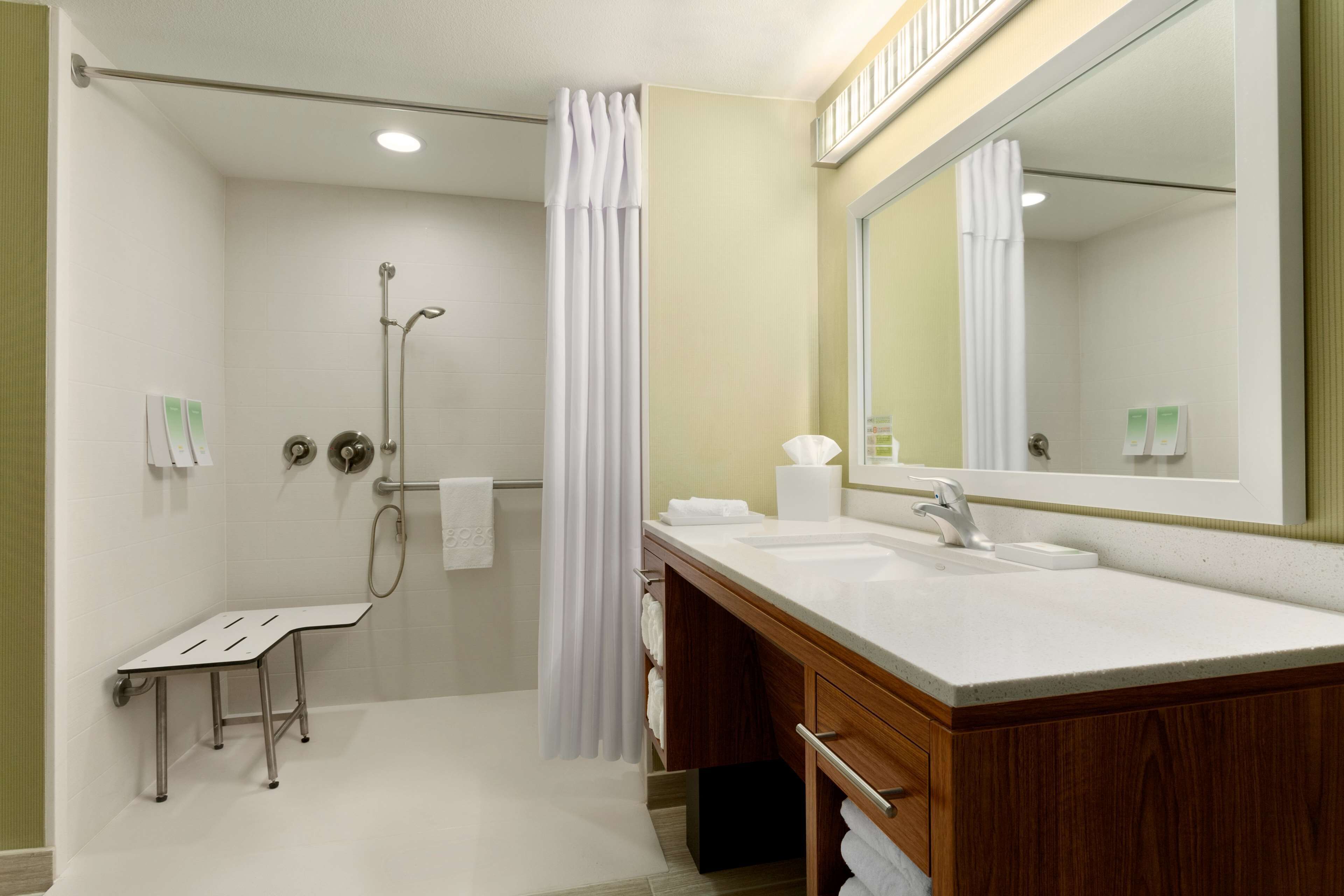 Un bany modern amb dutxa, un lavabo amb rentapisa i un mirall gran.