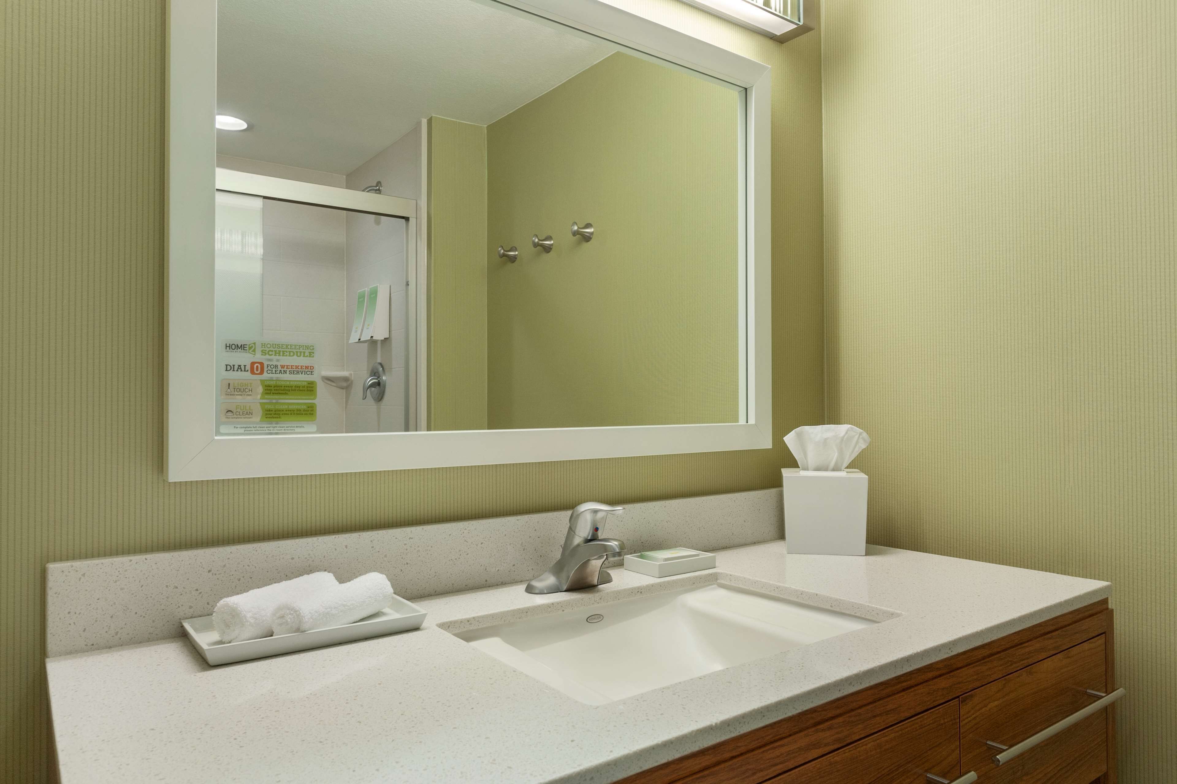 A bathroom with a white sink, a mirror, and a towel rack.