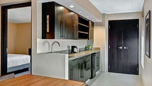 Een kleine hotelkamer met kitchenette, een bed en een donkerhouten deur.